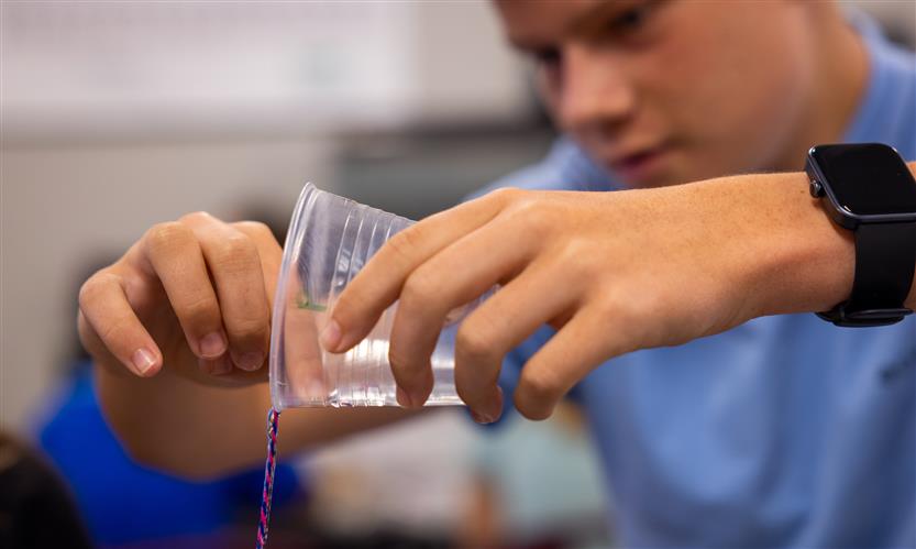 A boy pours water down a string